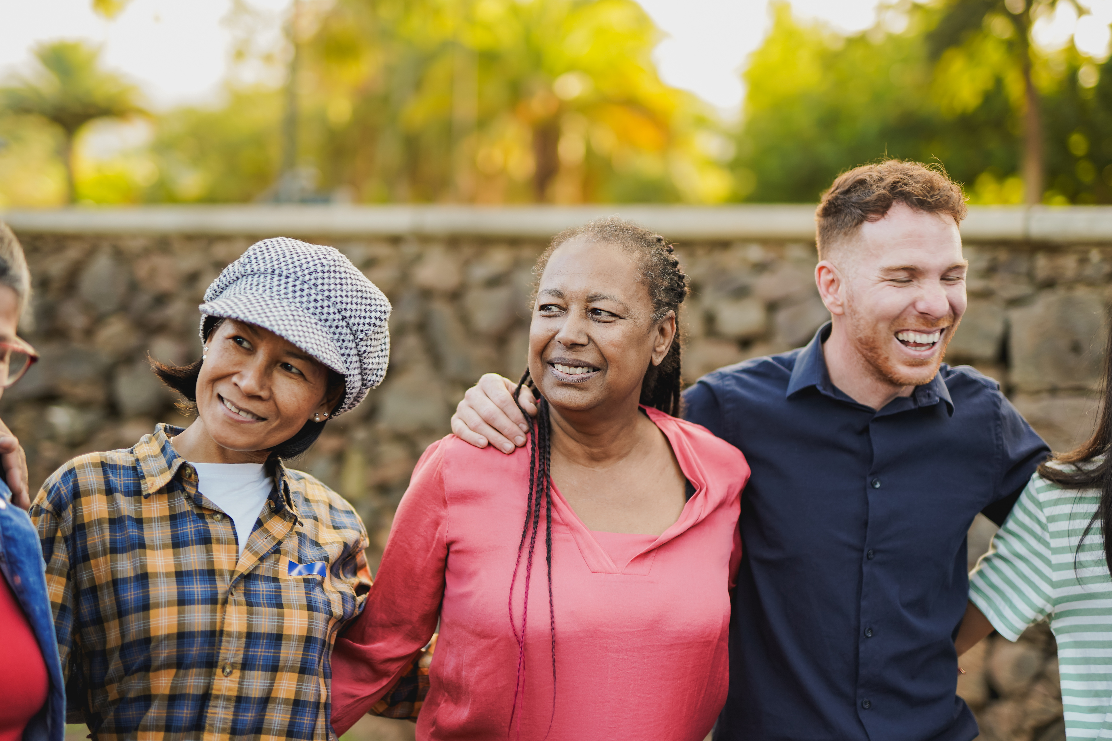Group of multi generational people hugging each other outdoor with city park in background